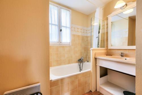 une salle de bain avec une baignoire et un lavabo dans l'établissement Les Maisons aux Restanques du Golfe de St Tropez - maeva Home - Maison Duplex 4 Pièces avec terrasse vue végétation 8 personnes - Prestige MAE-2842, à Grimaud