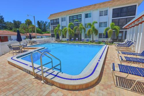 ein großer Pool mit Stühlen und ein Gebäude in der Unterkunft Updated Condo with Pool, Walk to Crescent Beach & Restaurants! in Sarasota