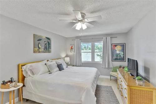 Schlafzimmer mit einem weißen Bett und einem Deckenventilator in der Unterkunft 2 bed 2 bath centrally located on Siesta Key in Sarasota