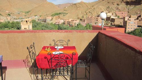 a red table and chairs on a balcony with a city at Kasbah Maison D’hôte Lalla Zahra in Aït Baha