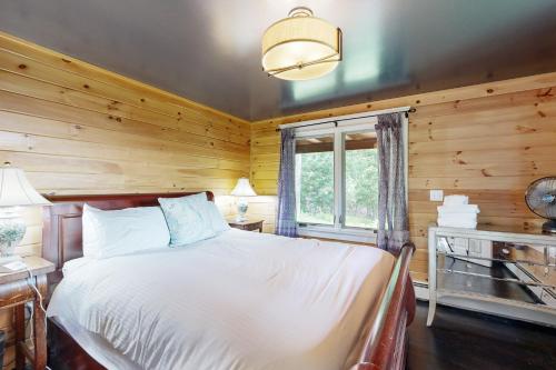 a bedroom with a bed with wooden walls and a window at Fox Lane Retreat in White River Junction