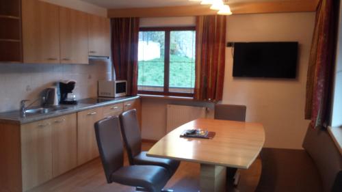 a kitchen with a wooden table and a table and chairs at Hotel Garnì Gardena - Appartments in Santa Cristina Gherdëina