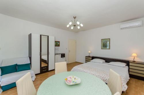 1 dormitorio con 2 camas, mesa y sillas en Apartments Jakov, en Jelsa