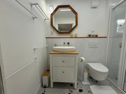a bathroom with a sink and a toilet and a mirror at Bánhiday H31 Beach house in Balatonakarattya
