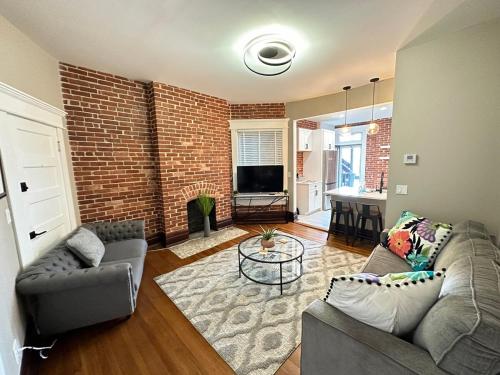 a living room with two couches and a brick wall at Big Brick 2 Bedroom apartment in Victorian Village in Columbus