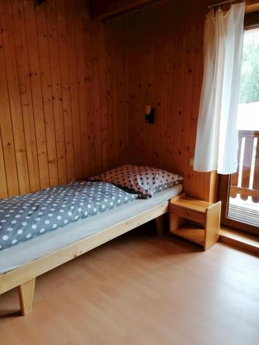 a bed in a wooden room with a window at Chata Porubka in Liptovský Mikuláš