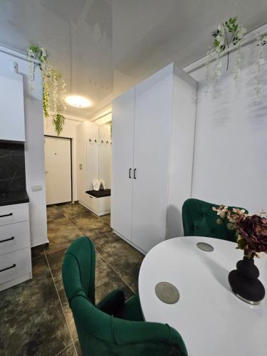 a kitchen with a white table and green chairs at EverGreen Apartment2 in Năvodari