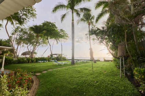 a park with palm trees and a view of the ocean at Perla de la Playa Beachfront Hotel in Tamarindo