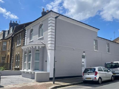 a white building with a car parked in front of it at The Lux Ville, Stunning 6 Bedroom Home in London in Plumstead