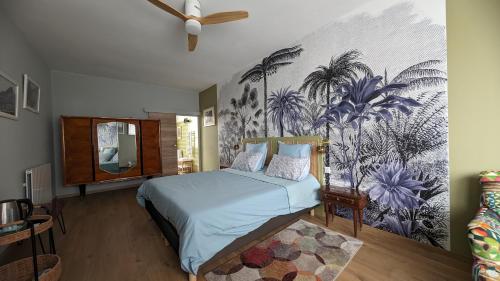 - une chambre avec un lit orné d'une fresque murale de palmiers dans l'établissement Rougetomette, à Nîmes