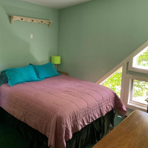 1 dormitorio con 1 cama con manta morada y ventana en Home in the woods, 