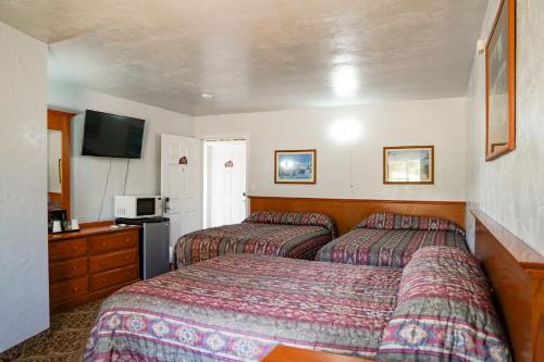 a hotel room with two beds and a television at Swiss Holiday Lodge in Mount Shasta