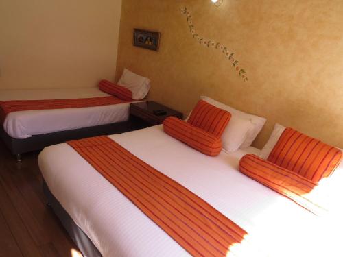 two beds in a room with orange and white sheets at Chalet Campestre la Peseta in Ubaté