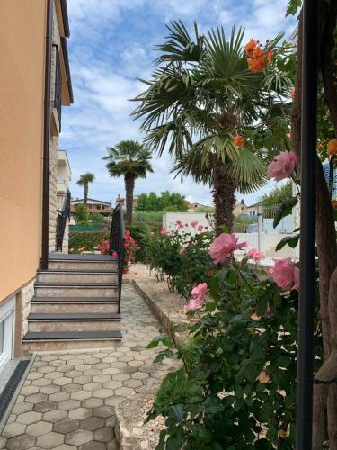 um jardim com flores cor-de-rosa, escadas e palmeiras em Apartments Kivi em Novigrad