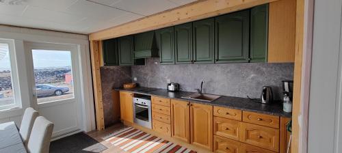 uma cozinha com armários verdes e um lavatório em Barents sea window em Ytre Kiberg