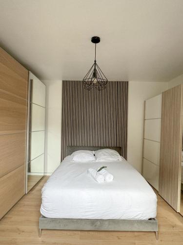 une chambre avec un grand lit blanc avec un lustre dans l'établissement Charmante Maison indépendante T3, à Suresnes