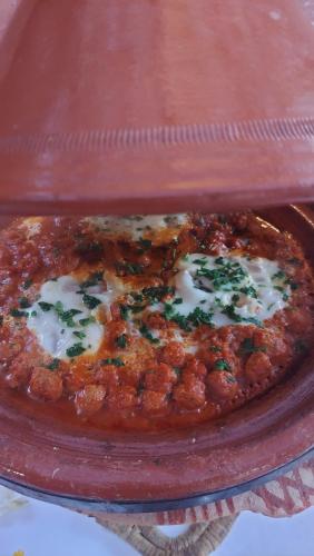 a pizza sitting on top of a red plate at Paradis Nomade in Azrarag