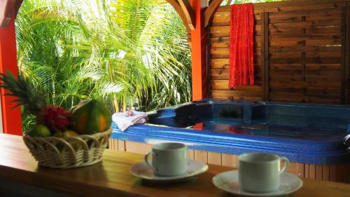a table with two cups and a bowl of fruit at Habitation Cantamerle in Capesterre-Belle-Eau