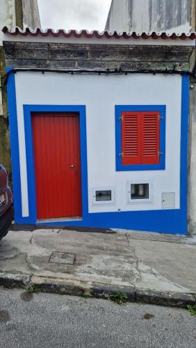 a red door and two windows on a building at Casa do Pescador 14 in Vila Franca do Campo