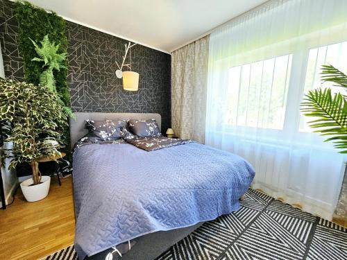 Cozy apartment close to the sea! في تالين: غرفة نوم بسرير لحاف ازرق ونباتات