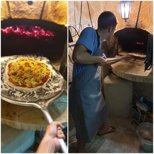 a man putting a pizza into a pizza oven at Apartment Carpe Diem with the best sea view, Utjeha Montenegro Mediterranean Eu in Masline