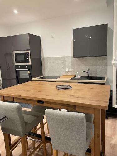 une cuisine avec une table en bois et deux chaises dans l'établissement Appartement et parking Saintes, à Saintes