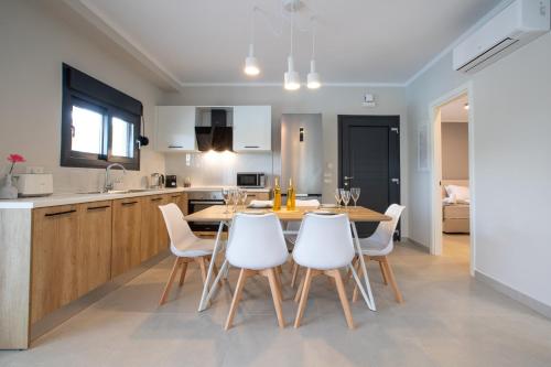 a kitchen and dining room with a table and white chairs at ONAR - LUXURY VILLAS in Argostoli