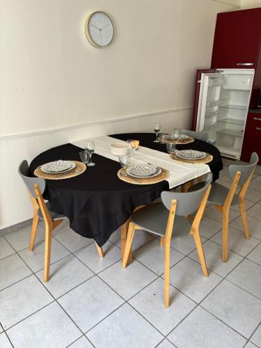 une table avec quatre chaises et une table noire avec des assiettes dessus dans l'établissement Petite maison à la campagne, à Mespaul
