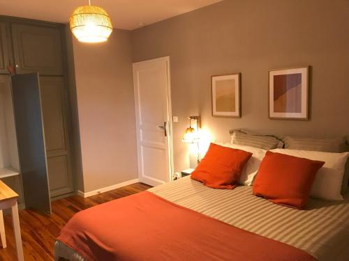 - une chambre avec un lit et deux oreillers orange dans l'établissement Chambre d'hôtes 'Sous le magnolia', à Oloron-Sainte-Marie