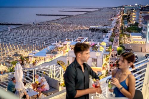 a man and woman standing on a balcony overlooking a beach at Hotel Marco Polo in Caorle