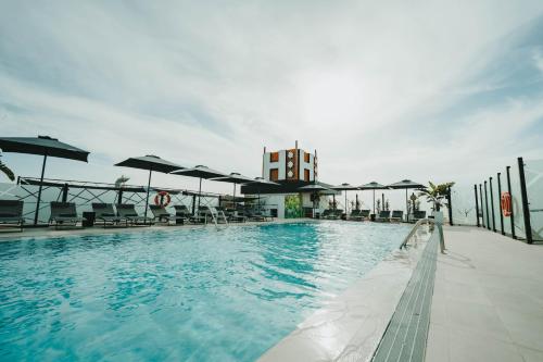 una gran piscina con sillas y sombrillas en Hotel Málaga Nostrum Airport en Málaga