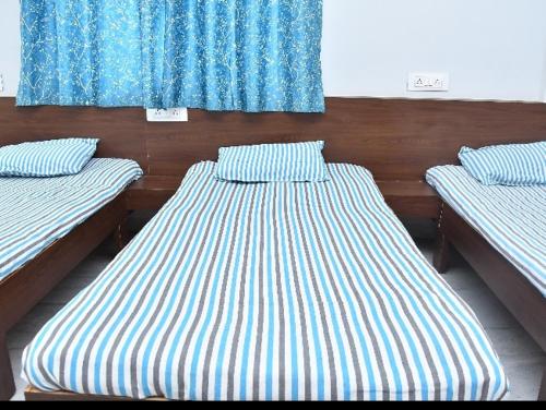 two beds in a room with blue and white stripes at Krishna yatri Niwas in Akalkot