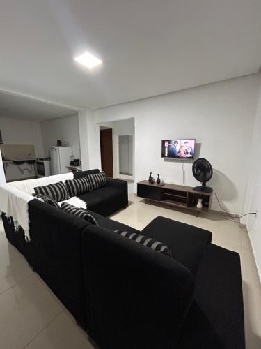 a living room with two black couches and a tv at Estadia Wolf Lencois in Lençóis