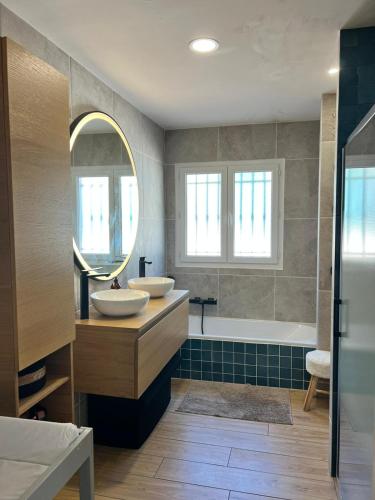 une salle de bain avec deux lavabos, un miroir et une baignoire dans l'établissement Villa avec piscine privée sur la french riviera, à Saint-Laurent-du-Var
