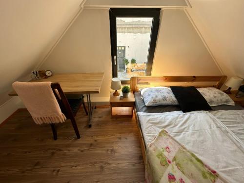 a bedroom with a bed and a desk and a window at Guszti Apartman in Pécs