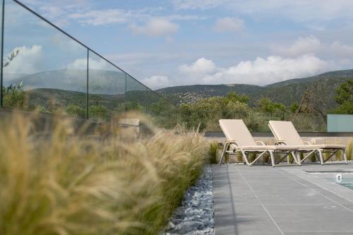 two chairs sitting on a patio with mountains in the background at ONAR - LUXURY VILLAS in Argostoli