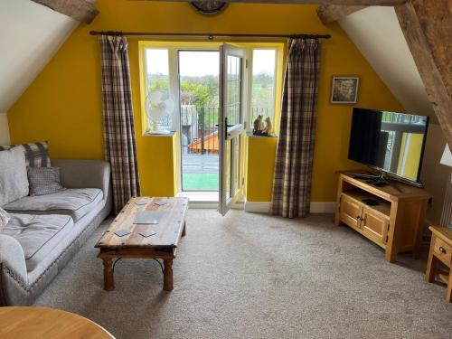 a living room with a couch and a tv and a table at Yew Tree Farm in Atherstone