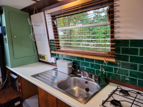 a kitchen counter with a sink and a window at Unique Canal Boat in London Centre for Family & Friends in London