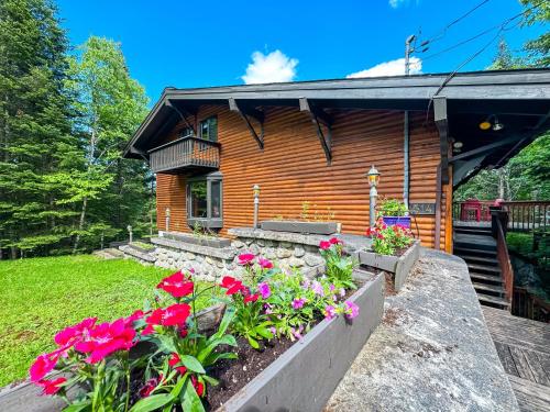 uma cabana de madeira com flores à frente em Chalet Suisse, SPA, Billard, Ski et Montagne em Sainte-Agathe-des-Monts
