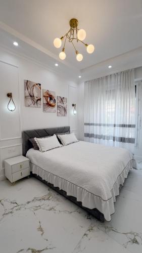- une chambre blanche avec un grand lit et un lustre dans l'établissement Appartement 3 PIECES NICE Promenade, à Nice