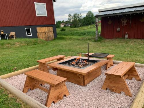 a picnic table and benches and a fire pit at Super cosy cottage in heart of Dalarna in Västra Fors