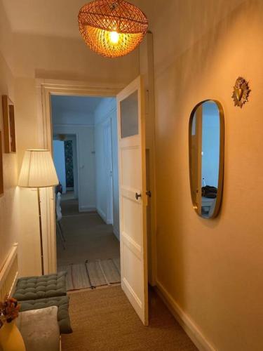 un couloir avec un miroir, une chaise et une lampe dans l'établissement T4 lumineux et spacieux Intra-Muros proche plages, à Saint-Malo