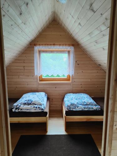 two beds in a small room with a window at Domek na Grządce in Bieńkówka