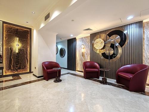 une salle d'attente avec des chaises rouges et un tableau sur le mur dans l'établissement ELAN RIMAL SADAF Suites, à Dubaï