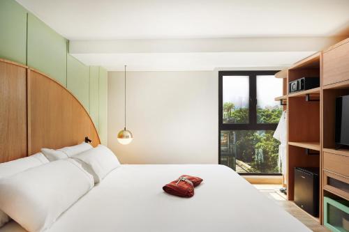 a bedroom with a white bed with a red purse on it at Wellcomm Spa & Hotel in Medellín