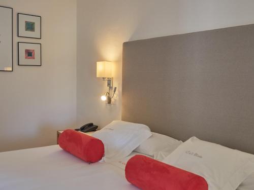 a bed with red and white pillows on it at Hotel Ca'l Bisbe in Sóller