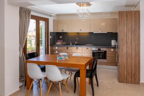a kitchen with a wooden table and white chairs at ALKIS LUXURY VILLA IRAKLiTSA in Kavala