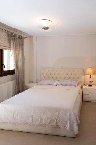 a bedroom with a large bed with a white bedspread at ALKIS LUXURY VILLA IRAKLiTSA in Kavála