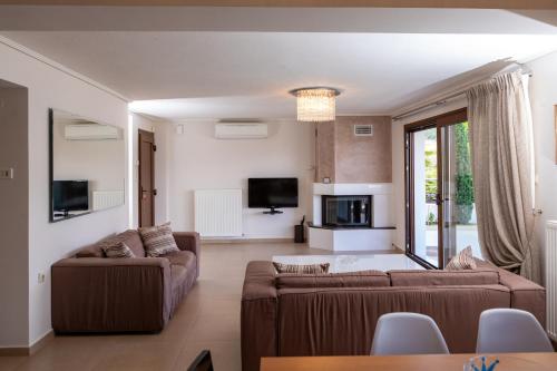 a living room with two couches and a tv at ALKIS LUXURY VILLA IRAKLiTSA in Kavala