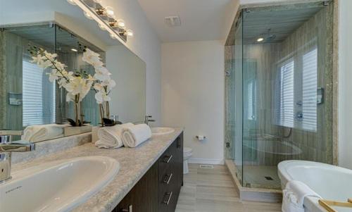 baño con 2 lavabos y ducha de cristal en Beartice Beach House, en Wasaga Beach